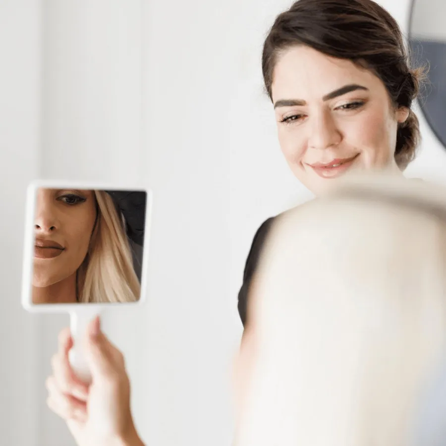 Patient reviewing her skin in a hand mirror during a consultation at a Perth cosmetic clinic